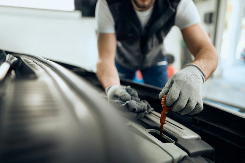 Close-up of car mechanic checking motor oil at repair shop.