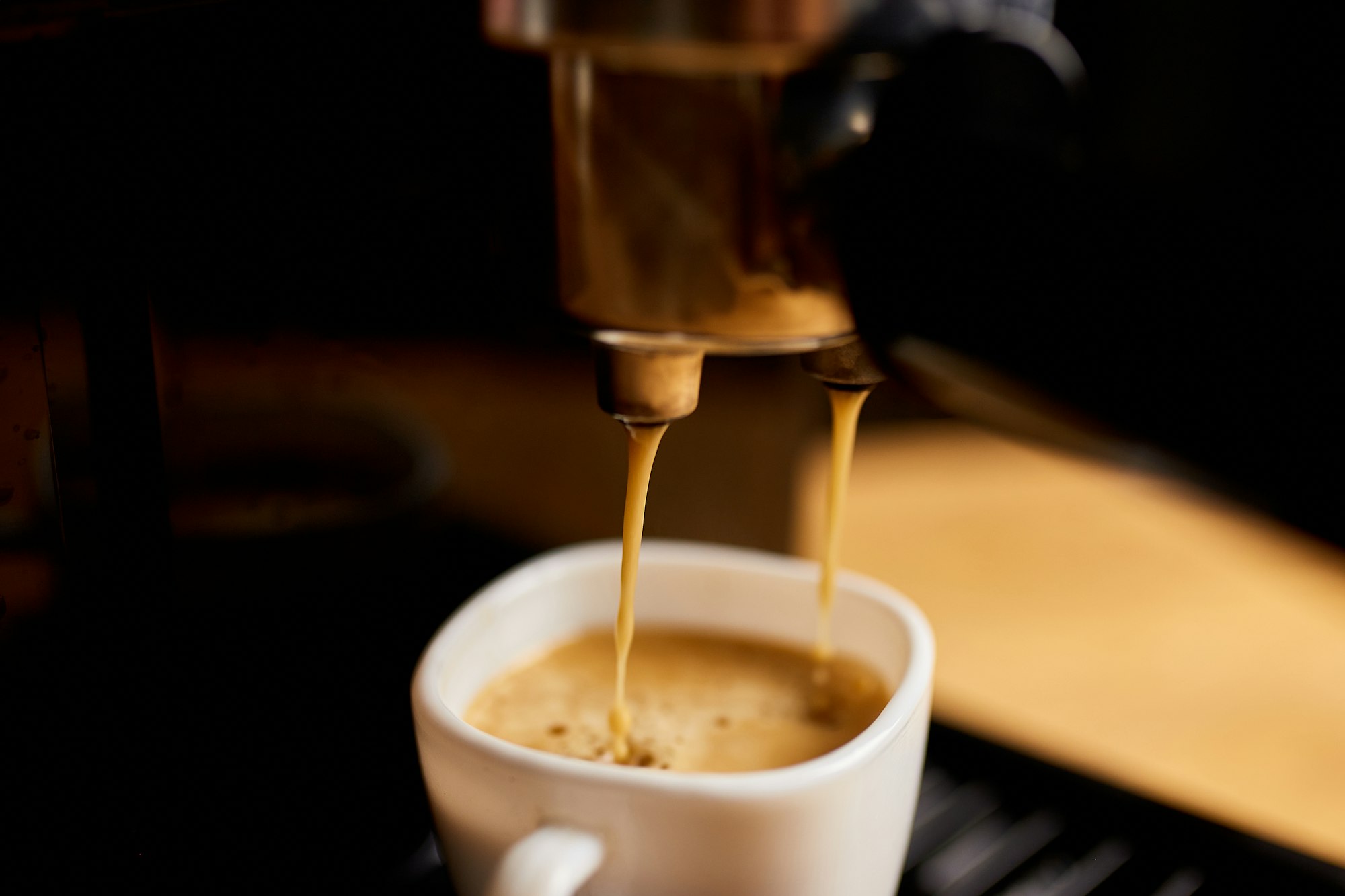Detail of a professional coffe maker dripping coffe into an empty cup in a cafeteria