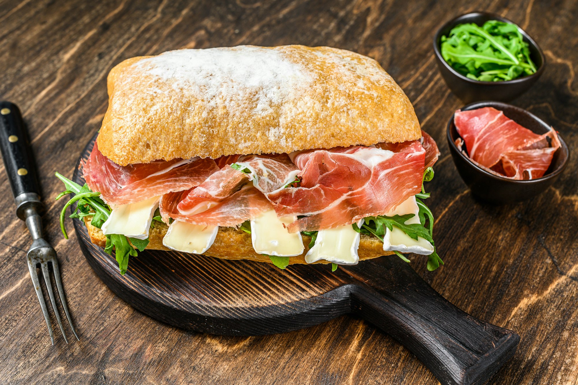 Jamon Ham Sandwich on ciabatta bread with arugula and camembert brie cheese.